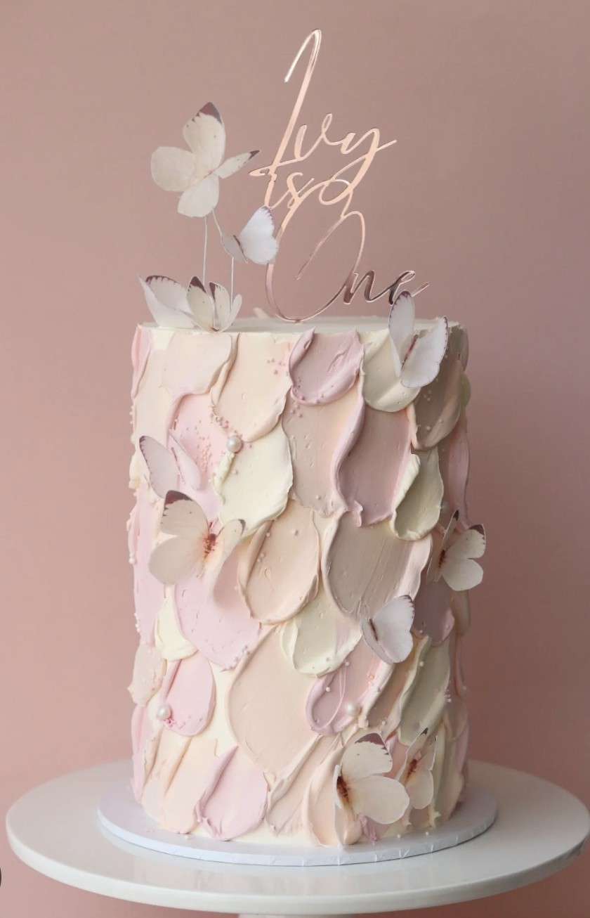 Tall round cake with overlapping palette-knife petal texture in blush tones and delicate butterfly accents